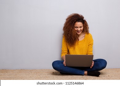 Portrait Of Happy Young Woman Sitting On Floor With Laptop