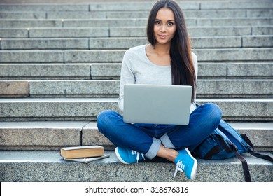 Portrait Of A Happy Young Woman Sitting On The City Stairs And Using Laptop Computer Outdoors