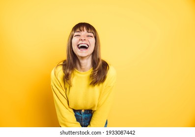 Portrait of happy young woman smiling at camera isolated on bright yellow background - Shutterstock ID 1933087442