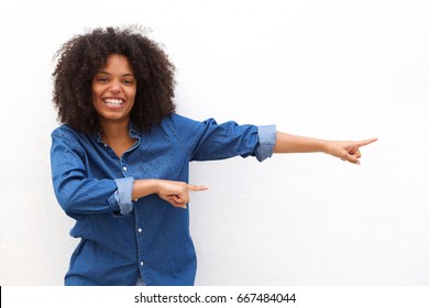 Portrait of happy young woman smiling and pointing against white background