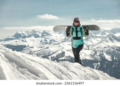 Portrait of happy young woman snowboarder is standing with snowboard in hands. Winter vacations or sports concept - Powered by Shutterstock