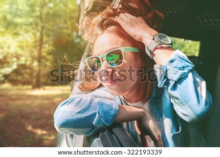 Happy young woman looking through the window car