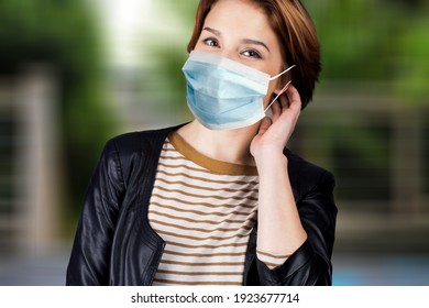 Portrait Of Happy Young Woman Wearing Face Medical Mask On Outdoor Background