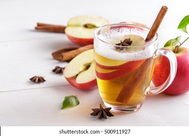 portrait of hard apple cider with cinnamon stick on white wooden table