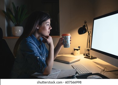 Portrait Of A Hardworking Woman Working On A Computer Late At Night While Drinking Coffee.