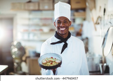 Portrait of head chef presenting salad in commercial kitchen - Powered by Shutterstock