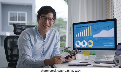 Portrait head shot young attractive asian man sitting smiling work multiple screen computer   smart tablet table desk at home in concept freelance data analyst  data scientist for business 