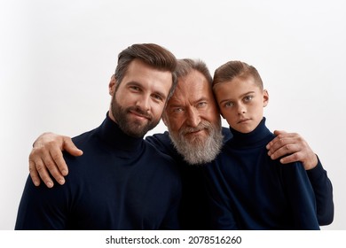 Portrait headshot of three generations of men hug cuddle show family love and unity together. Caring old grandfather embrace protect young adult grownup son and little grandson. Descendant.