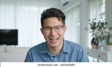 Portrait or headshot of young adult asian handsome man or model wearing eye glasses with cool hair big smiling confident and looking to camera with feeling happy and positive in living room at home.