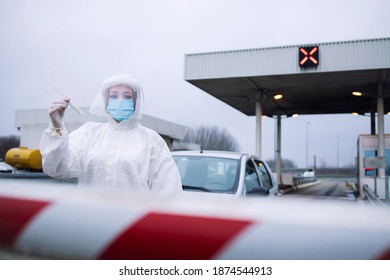 Portrait Of Health Care Medical Worker In Protective White Suit Standing At Border Crossing Checkpoint To Preform PCR Test On Passengers Due To Corona Virus Pandemic.