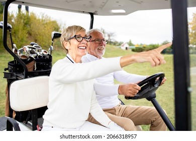 Portrait Of Healthy Active Senior Couple Driving Golf Car And Enjoying Free Time Outdoors.