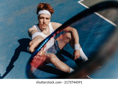 Portrait of a healthy athletic man in retro style with an athletic build with a tennis racket. Redhead guy playing tennis on the sports ground. Portrait of a healthy athletic man with an 