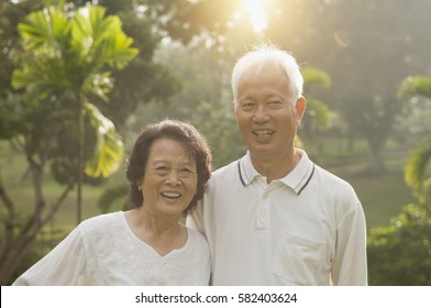 Portrait Of Healthy And Happy Asian Seniors Retiree Couple Having Activities At Outdoor Nature Park, Morning Beautiful Sunlight Background.