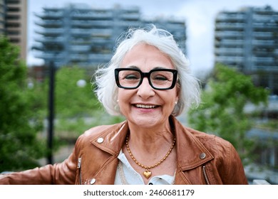 Portrait of a Healthy Happy Caucasian Senior Woman with Gray Hair Standing Outside in Front of a Garden Area at City. Old modern Grandmother Posing and Looking at Camera and Smiling. Copy Space - Powered by Shutterstock