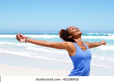 Portrait of healthy young african woman standing on the beach with her hands outstretched - Powered by Shutterstock