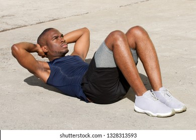 Portrait Of Healthy Young Black Man Doing Sit Ups Outdoors