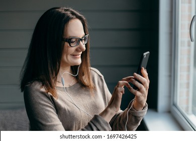 Portrait of healthy young brunette woman making facetime video calling with smartphone at home, using zoom meeting online app, social distancing, work from home, work remotely concept