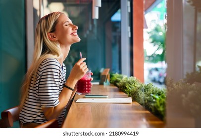 Portrait of a healthy young happy woman drinking a juice in cafe - Powered by Shutterstock