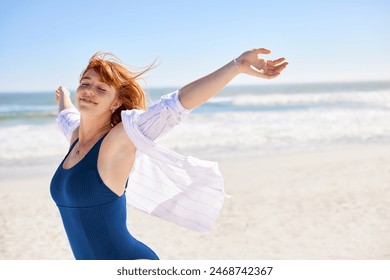 Portrait of healthy young woman breath deeply at the beach with outstretched arms and feeling the breeze with copy space. Happy smiling woman wearing swimsuit and casual shirt feeling fresh at sea. - Powered by Shutterstock