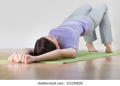 Portrait of healthy young woman practicing yoga exercise on mat at home