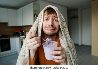 Portrait of heartbroken young man eating ice cream from bucket. Sad guy crying over breakup.