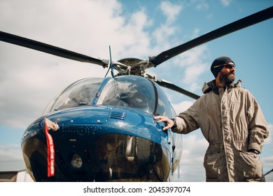 Portrait Of Helicopter Pilot Standing Near Vehicle In Field Airport.