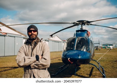 Portrait Of Helicopter Pilot Standing Near Vehicle In Field Airport.