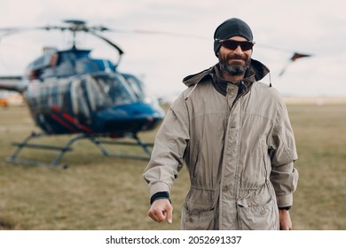 Portrait Of Helicopter Pilot Standing Near Vehicle In Field Airport.