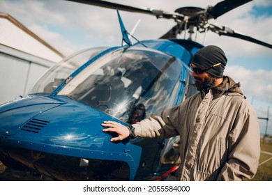 Portrait Of Helicopter Pilot Standing Near Vehicle In Field Airport.