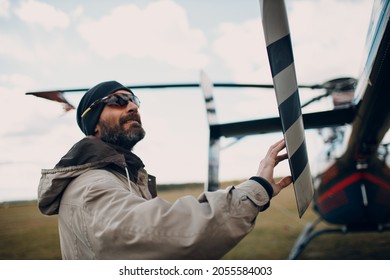 Portrait Of Helicopter Pilot Standing Near Vehicle In Field Airport.