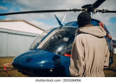 Portrait Of Helicopter Pilot Standing Near Vehicle In Field Airport.