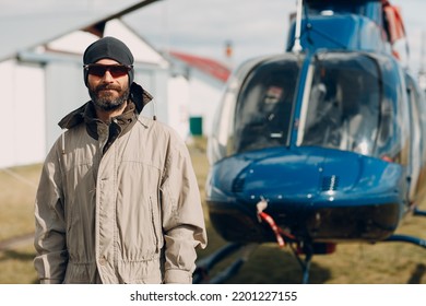 Portrait Of Helicopter Pilot Standing Near Vehicle In Field Airport.