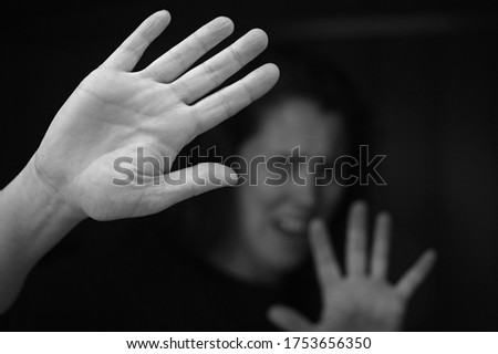Portrait of helpless battered adult woman protecting herself with hands screaming for help from the darkness.Isolated on black background.Domestic violence awareness concept. Real people. Copy space