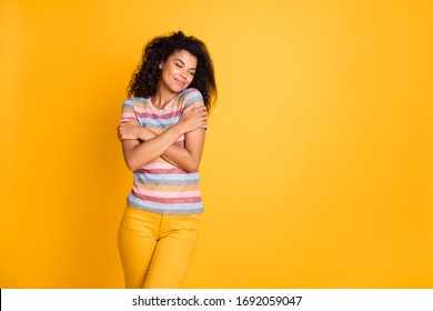 Portrait of her she nice attractive dreamy peaceful cheerful wavy-haired girl wearing striped tshirt hugging herself isolated over bright vivid shine vibrant yellow color background