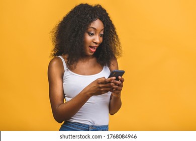 Portrait of her she nice attractive lovely winsome focused cheerful cheery wavy-haired african american black girl holding in hands phone chatting on web isolated over yellow background.