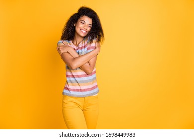 Portrait of her she nice lovely sweet gentle dreamy cheerful cheery wavy-haired girl wearing striped tshirt hugging herself isolated over bright vivid shine vibrant yellow color background