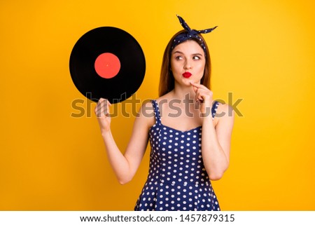 Portrait of her she nice-looking attractive lovely serious minded straight-haired lady holding in hands looking at round disc creating fest idea isolated on bright vivid shine yellow background