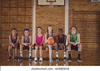 Portrait Of High School Kids Sitting On A Bench In Basketball Court