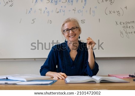 Portrait of high school math teacher sitting at desk working on assignments for students.