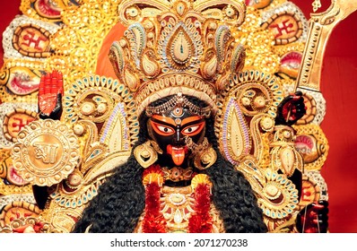 Portrait of Hindu Goddess Kali, heavily decorated with golden ornaments and zari (golden embroidery) works. Photo taken inside a Kali Puja pandal in Kalighat, Kolkata in 2021.