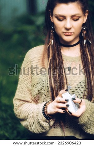 Portrait of a hippie witch girl who is in the forest and holds a deck of Tarot cards in her hands;. High quality photo