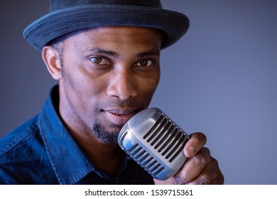 Portrait Of A Hipster Attractive Back Man About To Sing A Vintage Song. Isolated Male Singing Ethnic Cultural Songs. Young African American Singer Holding A Trendy Microphone. Compose And Create Lyric