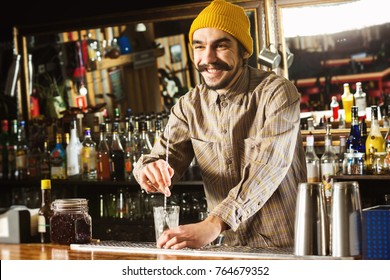 Portrait Of Hipster Barman Mixing A Cocktail With A Spoon At Bar Background.