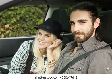 portrait of hipster couple in car looking at camera smiling. Focus on man