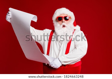 Portrait of his he attractive amazed fat white-haired Santa holding in hands reading wish present gift list pout lips order isolated bright vivid shine vibrant red burgundy maroon color background