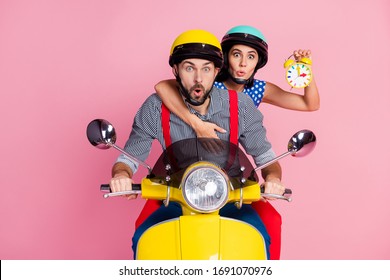 Portrait of his he her she nice attractive worried amazed couple driving moped hurry-up rush holding in hands clock pout lips omg isolated over pink pastel color background