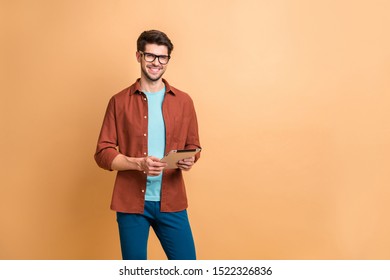 Portrait of his he nice attractive cheerful cheery successful content brunette guy holding in hands digital e-book browsing web app isolated over beige color pastel background