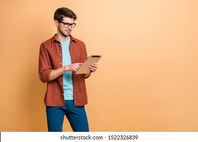 Portrait of his he nice attractive calm focused successful content brunet guy holding in hands reading digital e-book isolated over beige color pastel background