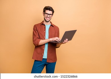 Portrait of his he nice attractive cheerful cheery successful content smart clever brunet guy agent broker holding in hands laptop working isolated over beige color pastel background - Powered by Shutterstock