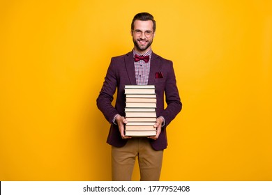 Portrait of his he nice attractive cheerful intelligent guy professor holding in hands many book academic learning isolated over bright vivid shine vibrant yellow color background